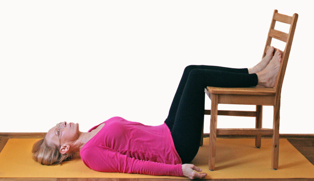 kobieta-w-pozycji-relakacyjnej-joga-dla-seniorów-relaks-w-pozycji-leżącej-z-wykorzystaniem-krzesła